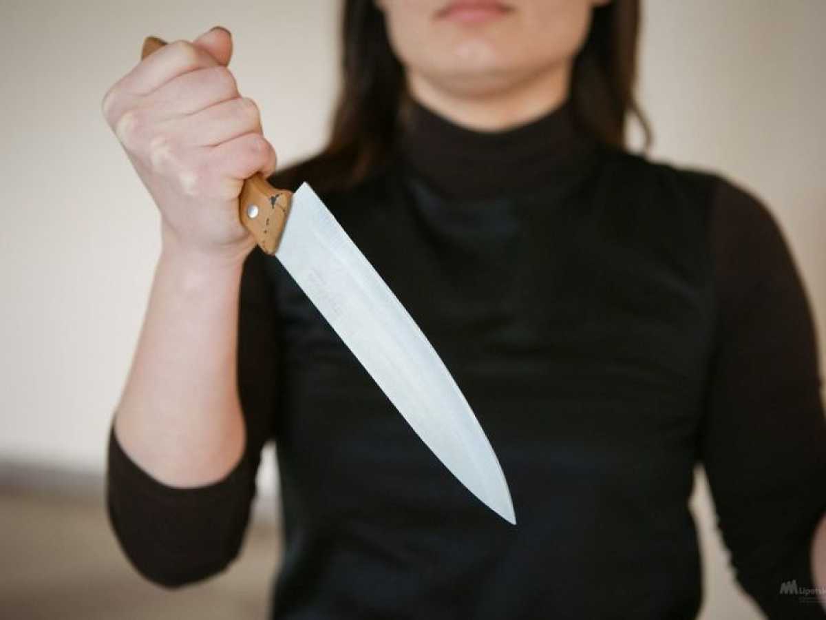 Нанесение ножевых. Женщина замахивается ножом.